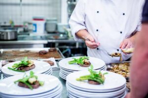 Man in White Top Standing Beside Plates